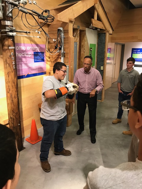 Carpentry Sophomore Elijah Roque dons heavy insulated electrical gloves for a power line demonstration at the Energize CT center.