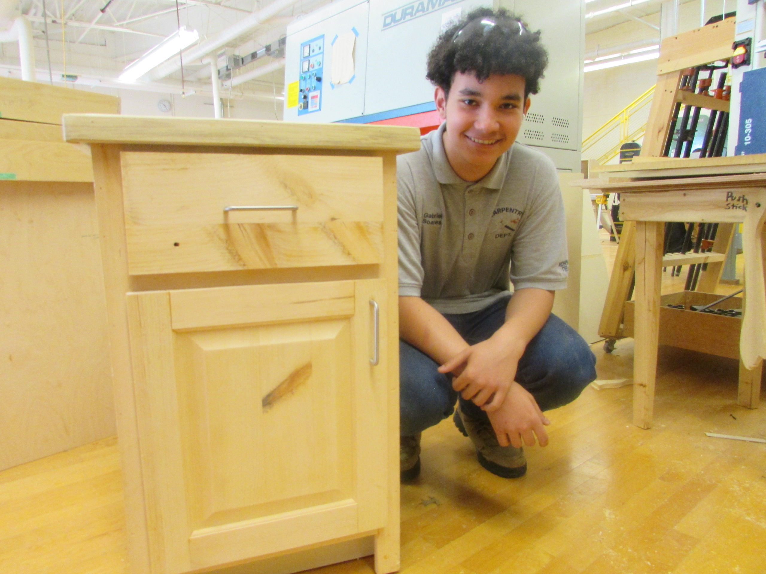 Carpentry student posing next to cabinet
